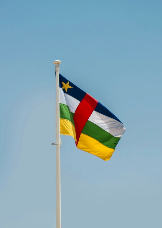 the multi - colored flag flying against a blue sky