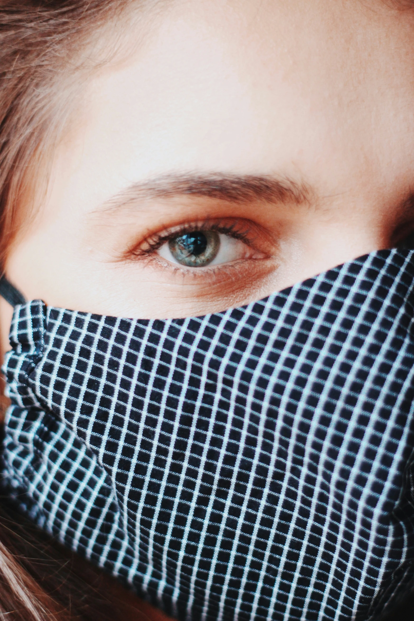 a woman wears a fabric face mask with blue grid pattern