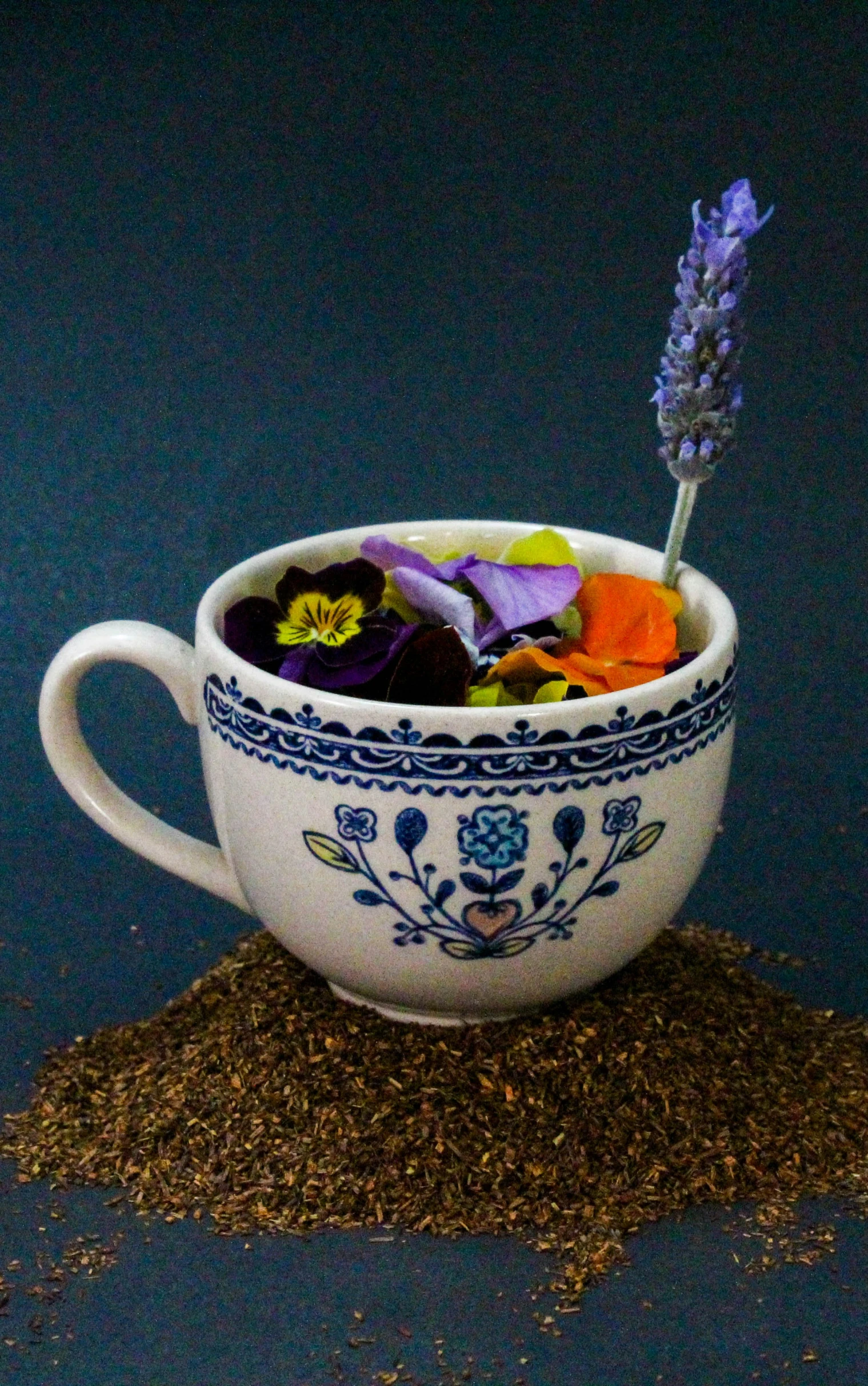 a cup filled with dirt and flower sitting on top of it