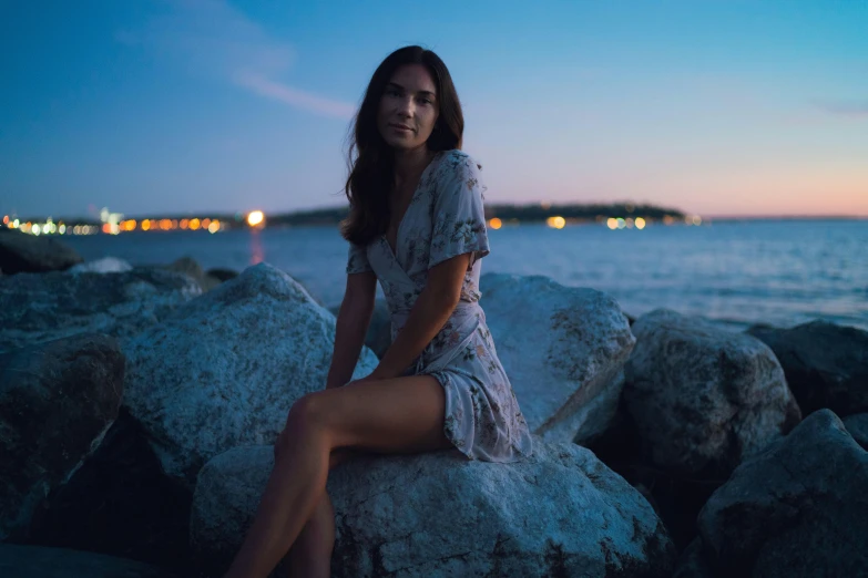 a beautiful young woman sitting on rocks at night