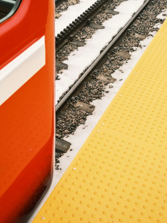 there is only one side of the yellow platform next to the red train