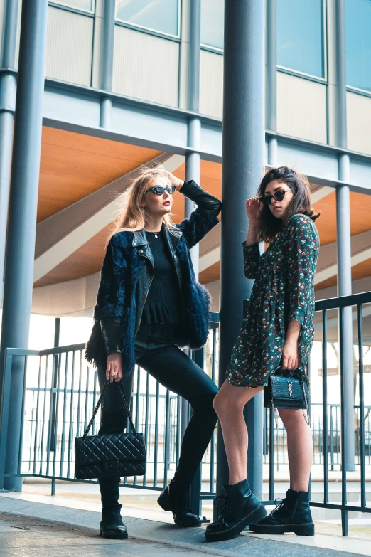 two young women stand next to each other on a sidewalk