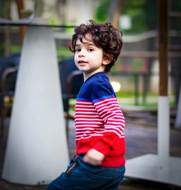 little boy walking in front of a sculpture