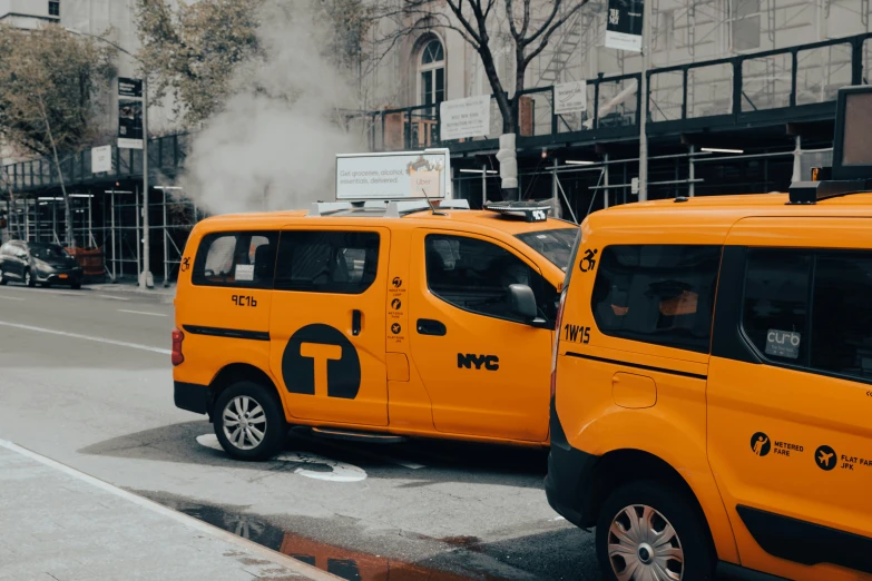 two yellow taxi cabs sitting in front of a tall building