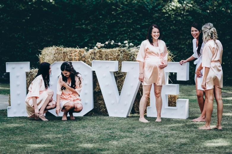 two woman standing next to a giant sign made out of hay