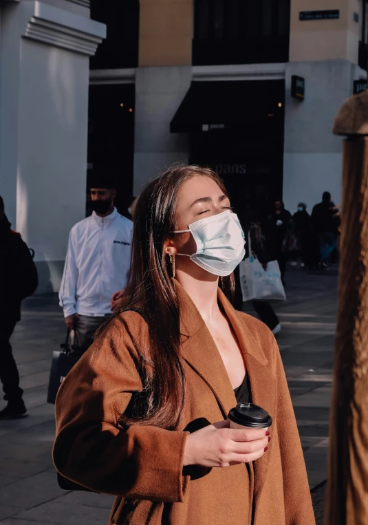 a woman wearing a face mask while standing next to a building