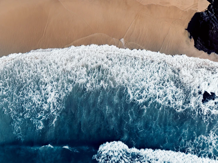 an aerial view of a wave coming on the beach