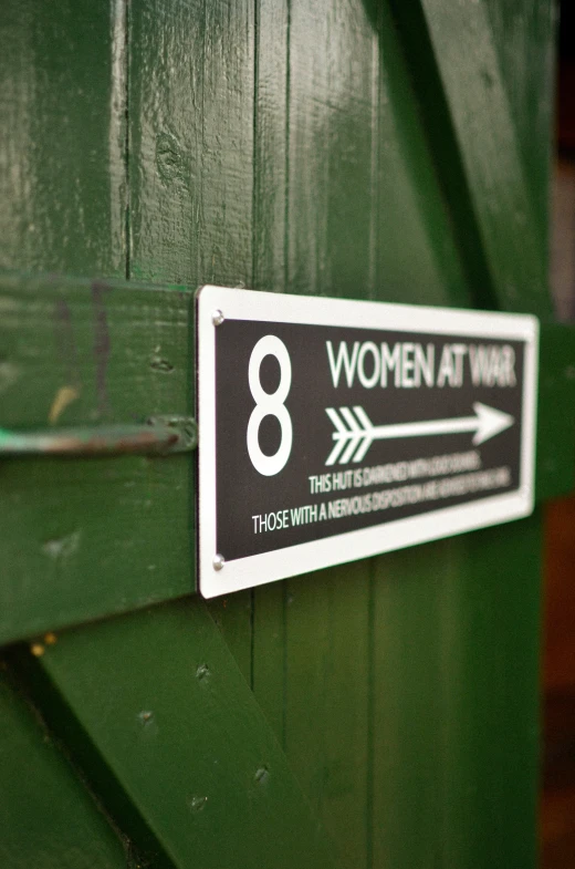 an arrow and women at work sign are on the green wall