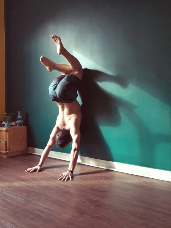 a man is standing on his handstand on a wood floor