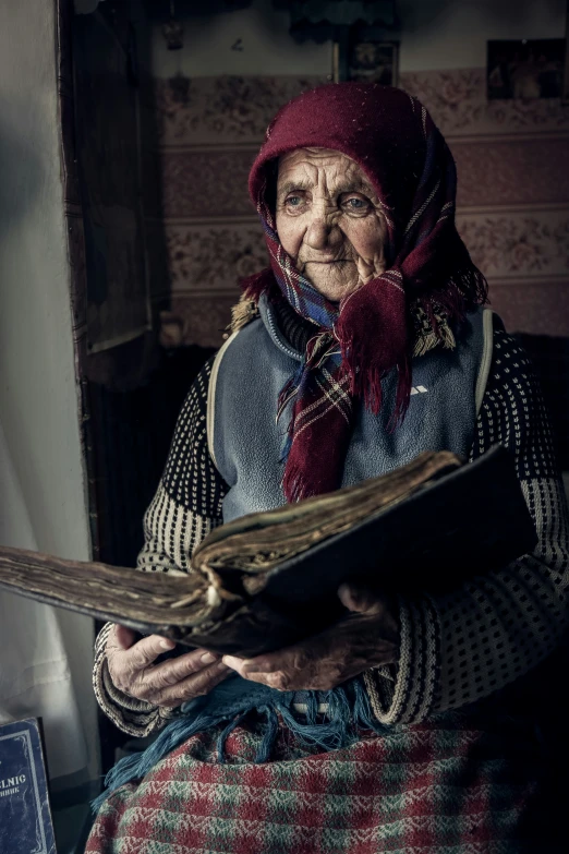 an older woman wearing a scarf is holding a book