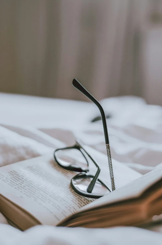 an open book and glasses on a bed