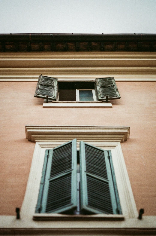 two windows on a red building with shutters open