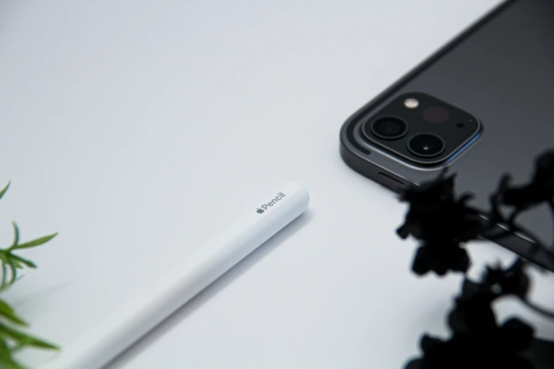 a phone sitting on a table with a pen next to it