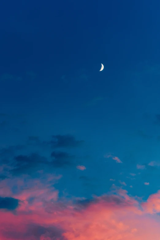 a sunset view with a half moon and pink clouds