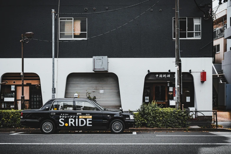 a black car parked next to a building in the rain