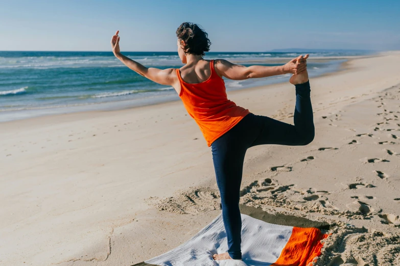 a woman in an orange and black top is doing yoga