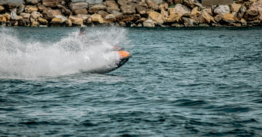 the surfboarder is spraying up water near some rocks