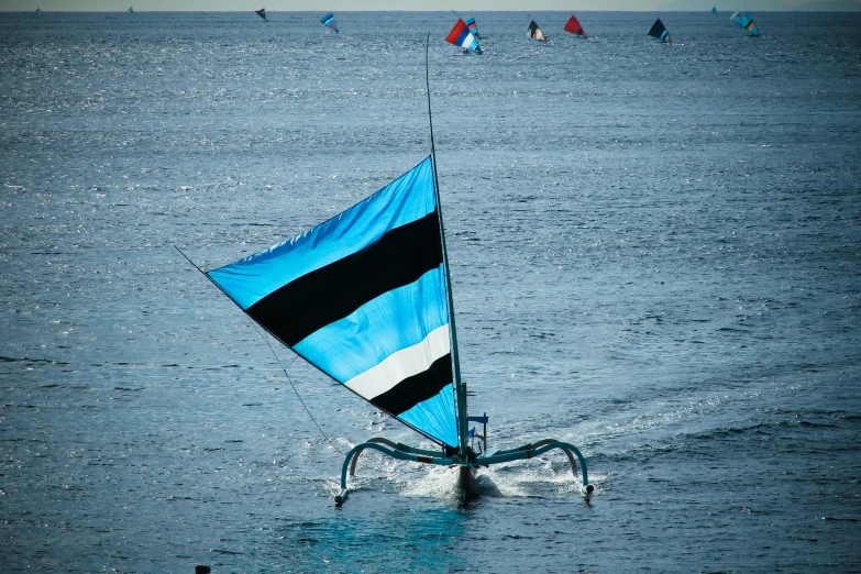 a blue sail boat is in a body of water