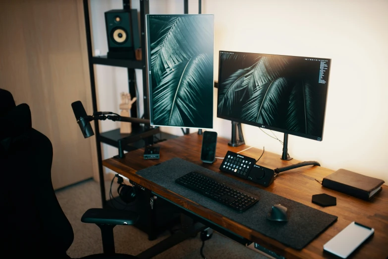 a desk with keyboard and two monitors showing screens