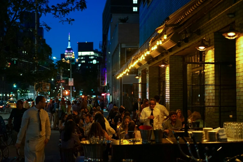 people outside at outdoor restaurant area on city street at night