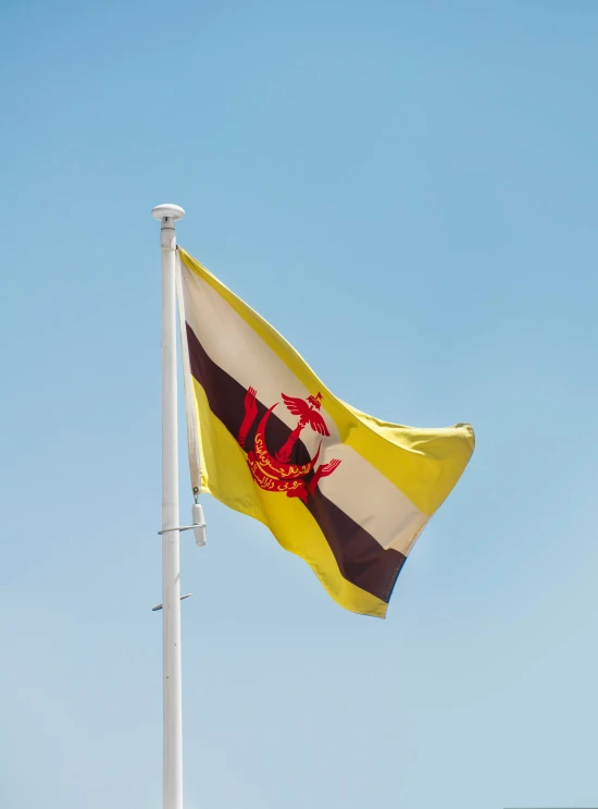 flag flying high on flagpole next to blue sky