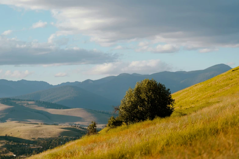 the view from the top of a hill with rolling hills and mountains in the background