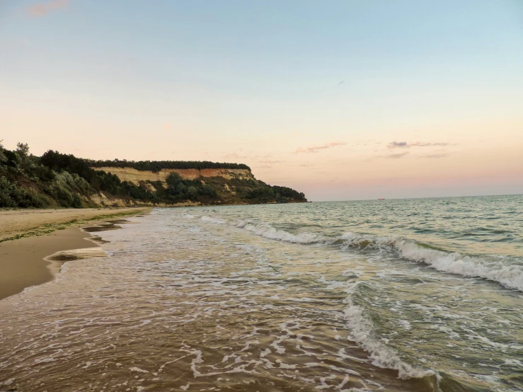 a rocky shoreline with waves washing in front of the rocks and beach