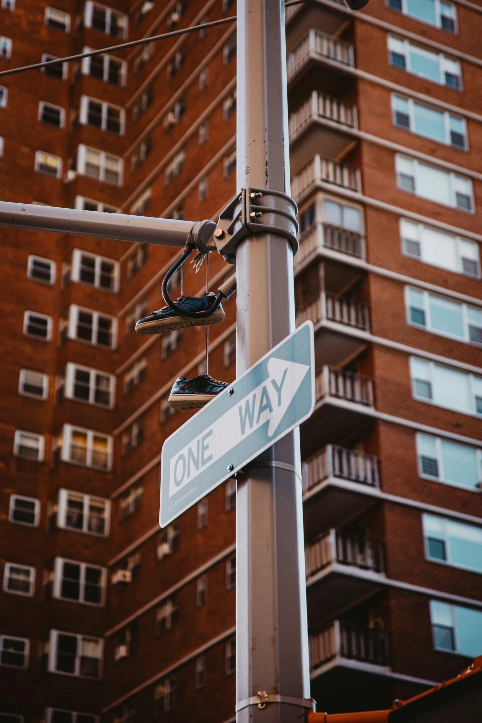 street sign with lightpost on city street in front of tall apartment building