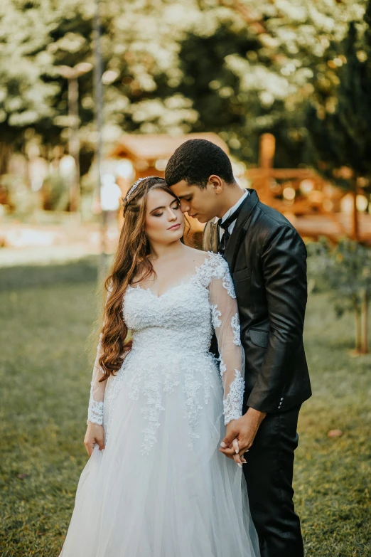 a bride and groom stand in the grass, together