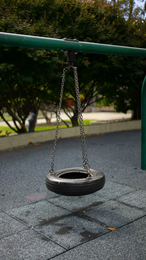 the swinging wheel is on the ground next to a playground