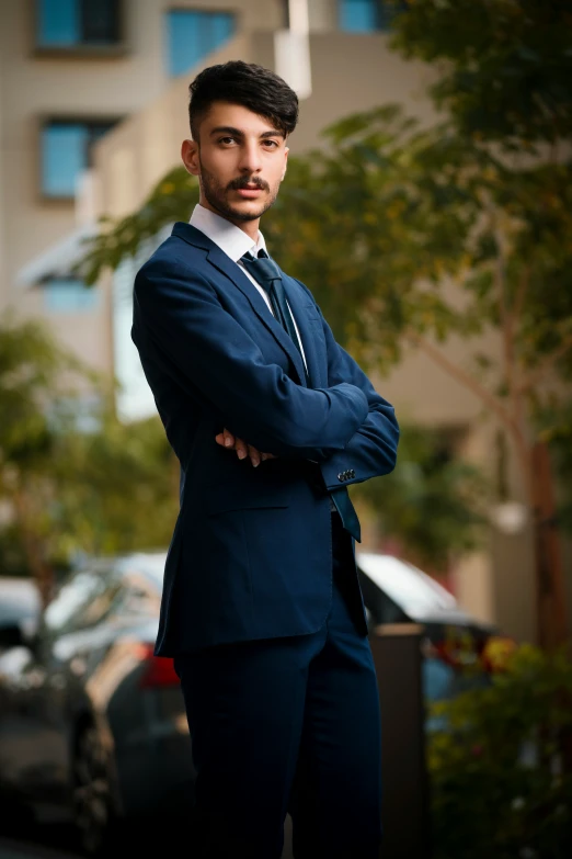 a man wearing a suit and tie, standing near parked cars