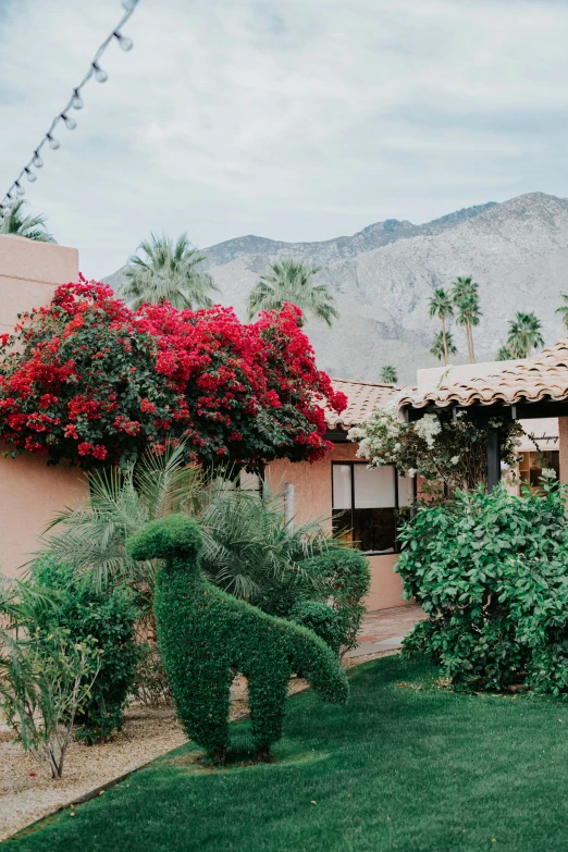 a large house with red flowers and trees next to it