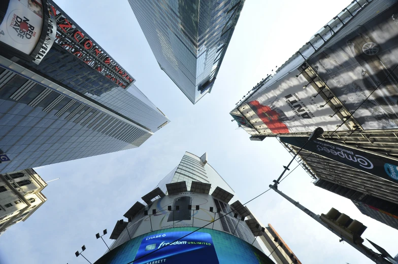 view looking up at tall buildings and signs with a sky background