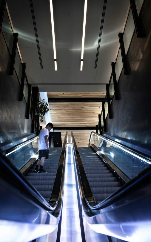 two people are riding the escalators near a wall