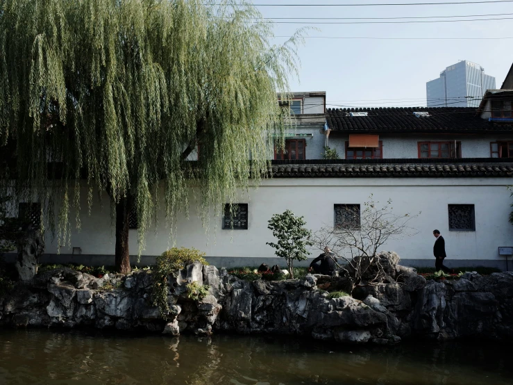 the man is walking through the park by the river