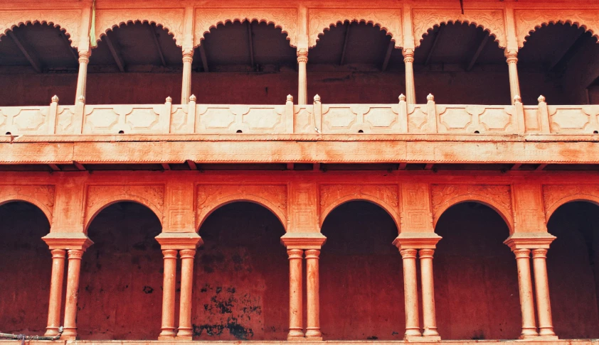 several pillars stand in a stone building next to a red wall