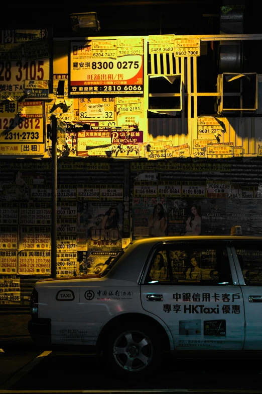 a car is parked near a building that has a large number of signs on it