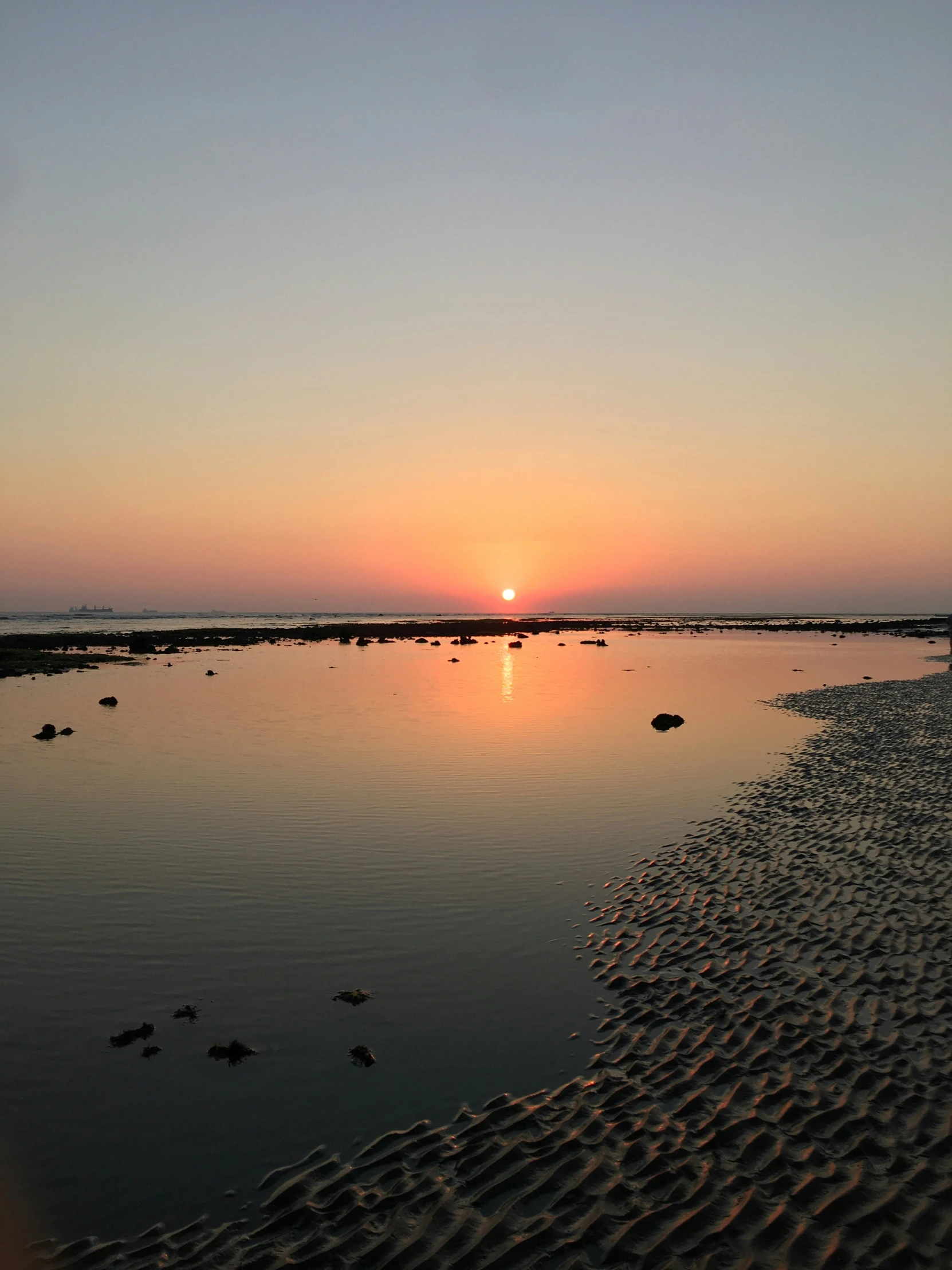 a bright sunset reflecting the sky and water on a beach