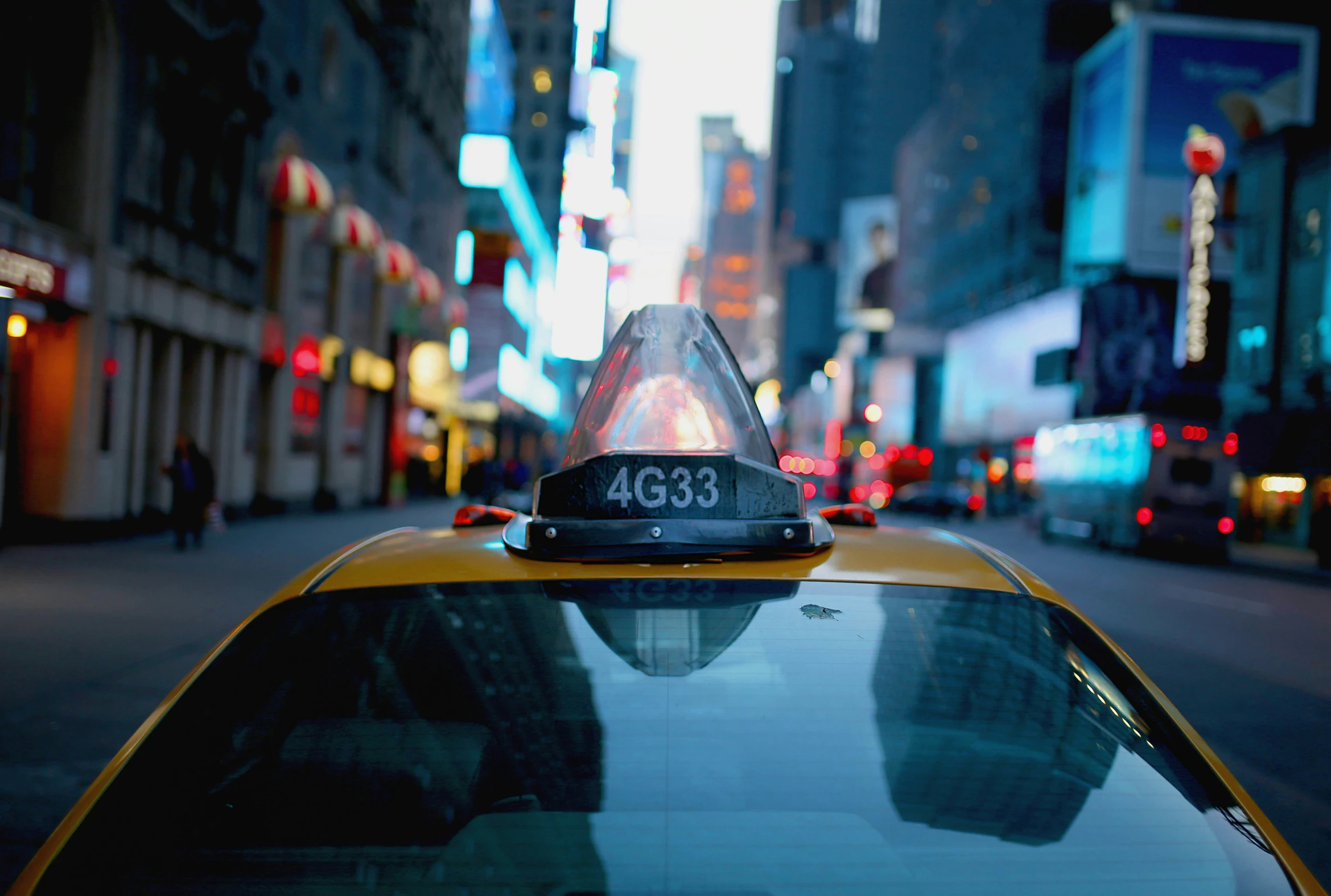 a taxi cab on a city street with cars behind it