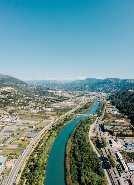 an aerial view of a freeway running between a river and city