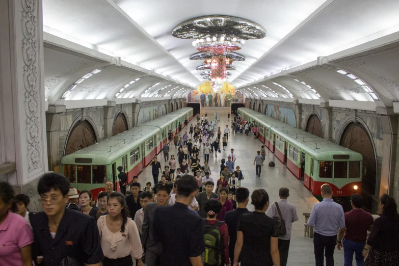 a crowded train station with many people coming out of the platforms