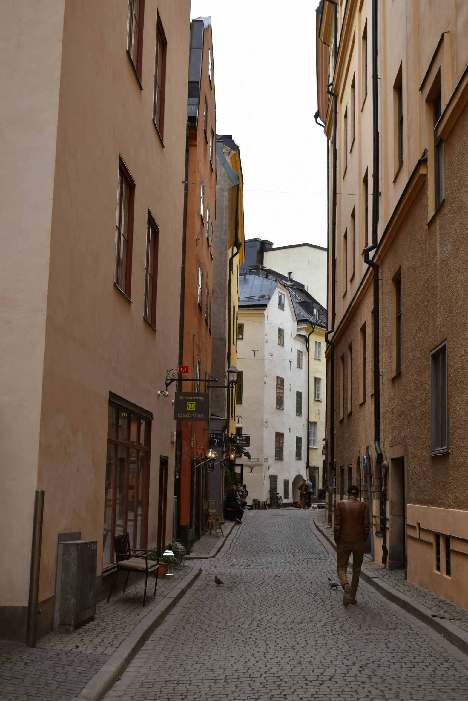 a man walking down a street past several tall buildings