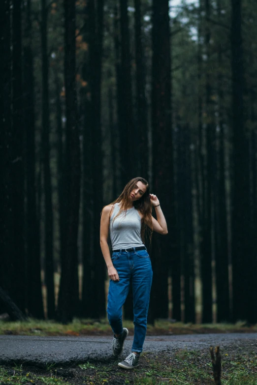 a woman standing in a forest near some trees