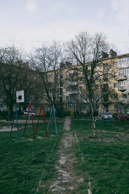 a park with various wooden swings, grass, and trees