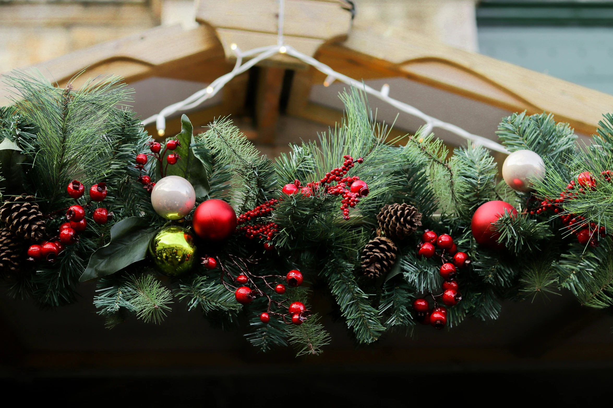 a close up of a wreath made from firs, ornaments and berries