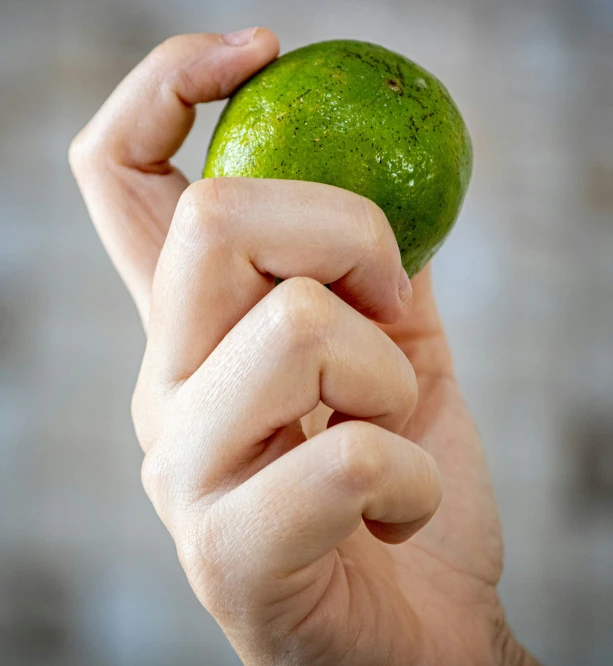 the hand holds the green fruit up high