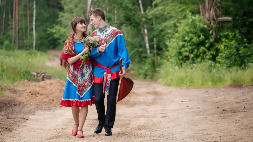 a couple is standing in the middle of a dirt road