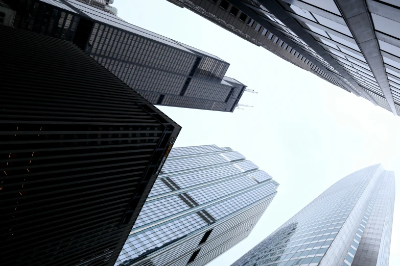 looking up at skyscrs from the ground, against a blue sky