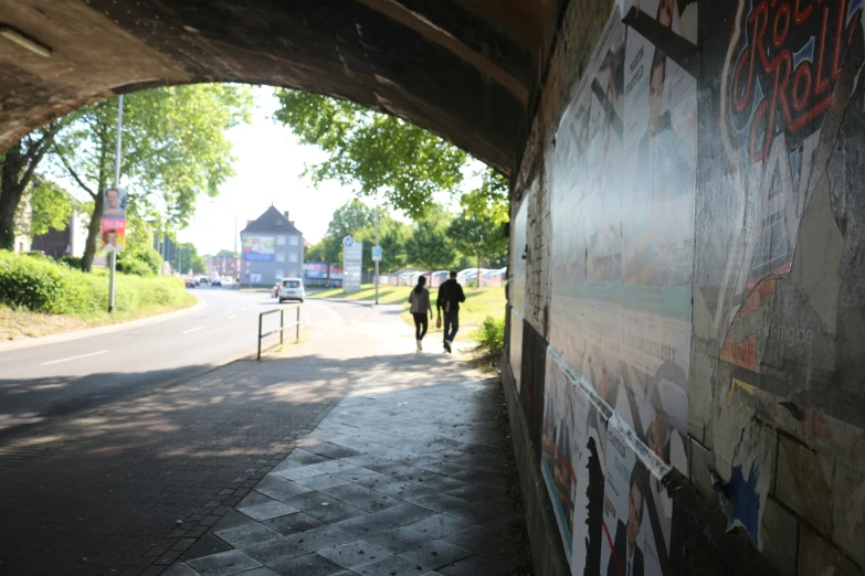 two people walking through a tunnel under a bridge