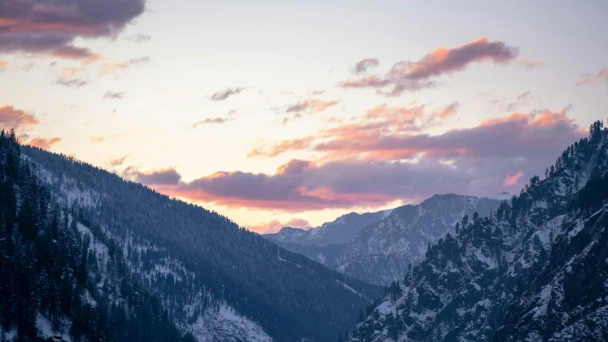 snow covered mountains are pictured against a sunset